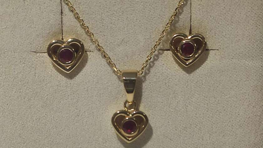 un juego de colgante y pendientes con corazones pequeños en oro amarillo y rubies