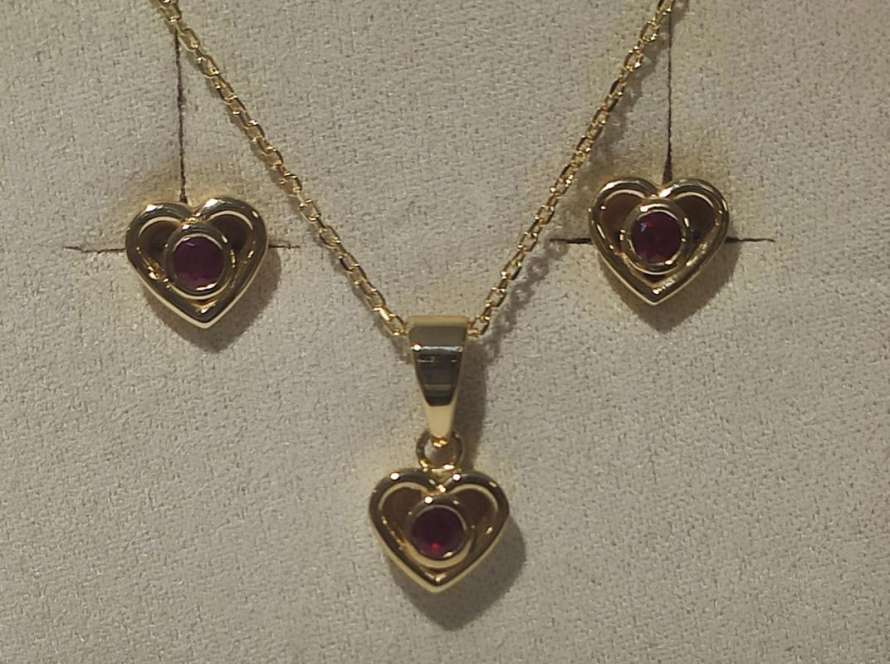 un juego de colgante y pendientes con corazones pequeños en oro amarillo y rubies
